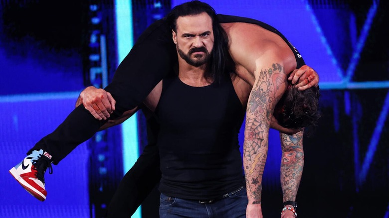 Drew McIntyre carries a beaten and battered CM Punk.