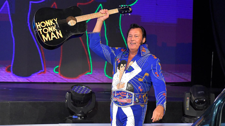 The Honky Tonk Man holds up a black guitar with his name written on it