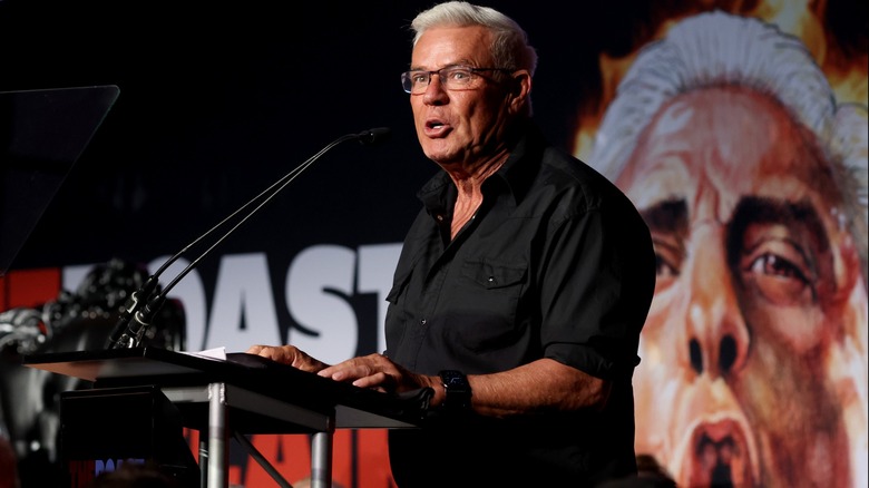 Eric Bischoff speaks in front of a Ric Flair backdrop