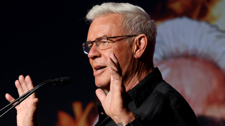 Eric Bischoff raising his hands behind a podium