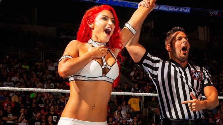 Eva Marie tiene la mano levantada por un árbitro tras una victoria en 