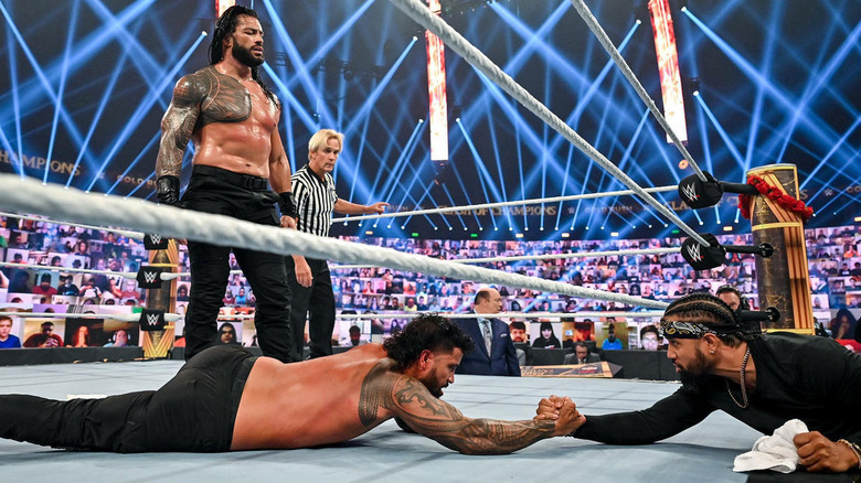 Roman Reigns looks as Jey and Jimmy Uso grab hands