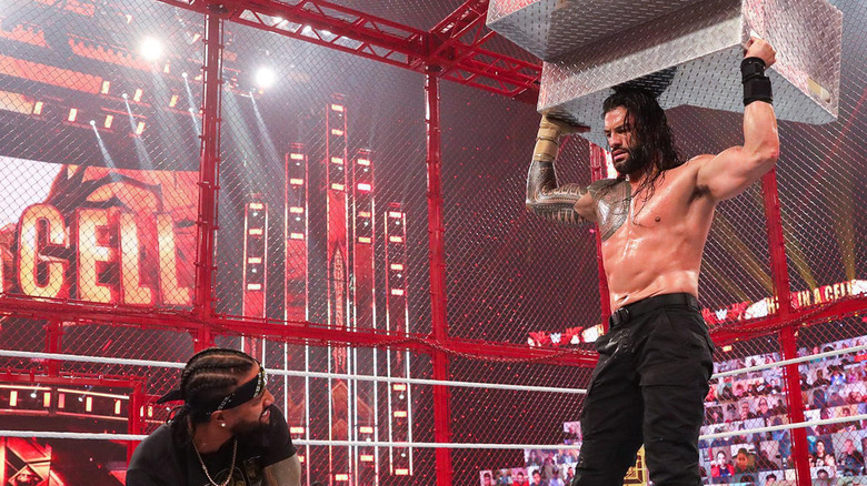 Roman Reigns holds stairs over Jey Uso