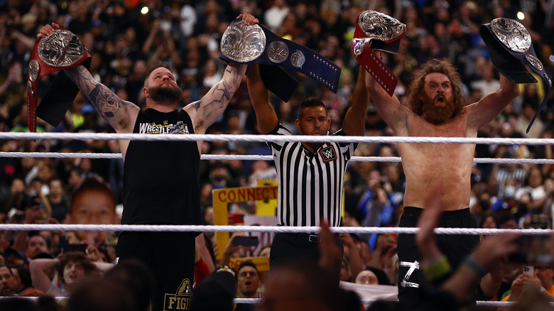 Kevin Owens and Sami Zayn holding up the Undisputed WWE Tag Team Championship titles