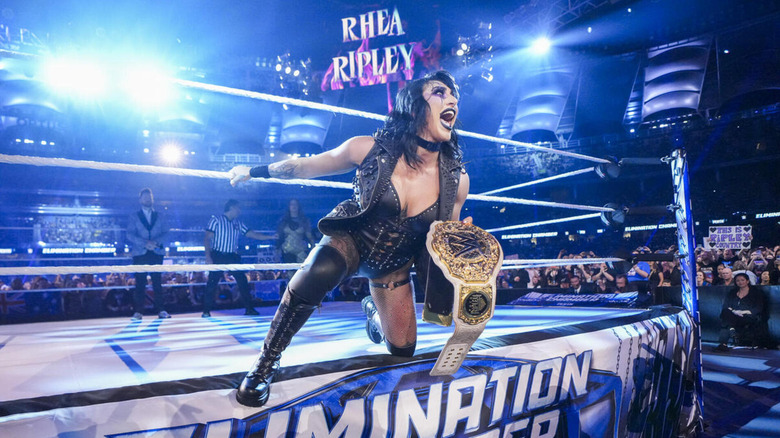 Rhea Ripley shouts as she hangs off of the apron during Elimination Chamber 2024, WWE Women's Championship in hand.