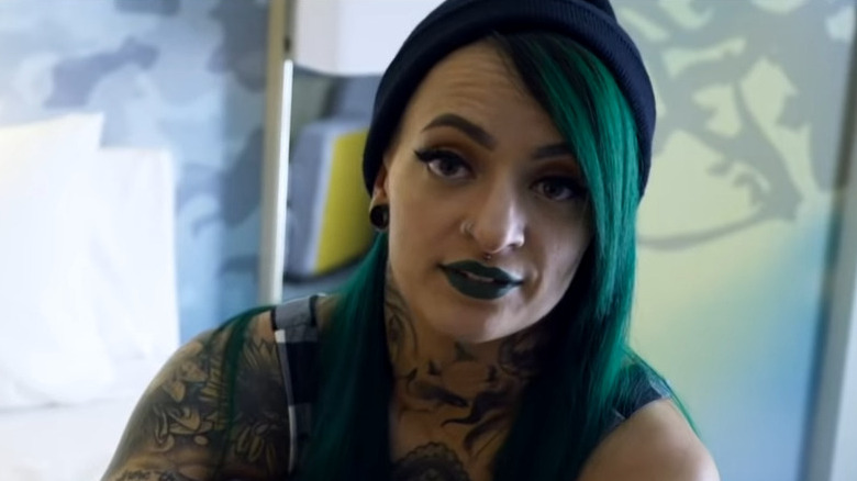 Ruby Riott sitting on a bed in a hotel