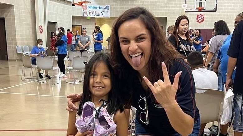 Thunder Rosa doing metal sign with kid