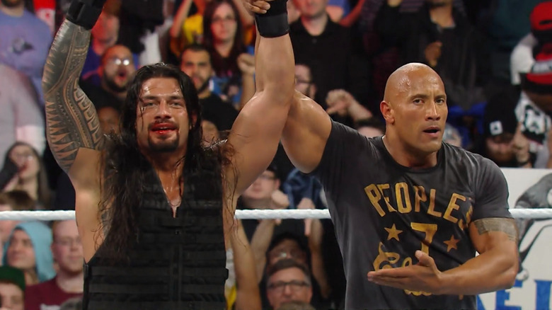 The Rock raises Roman Reigns' arm