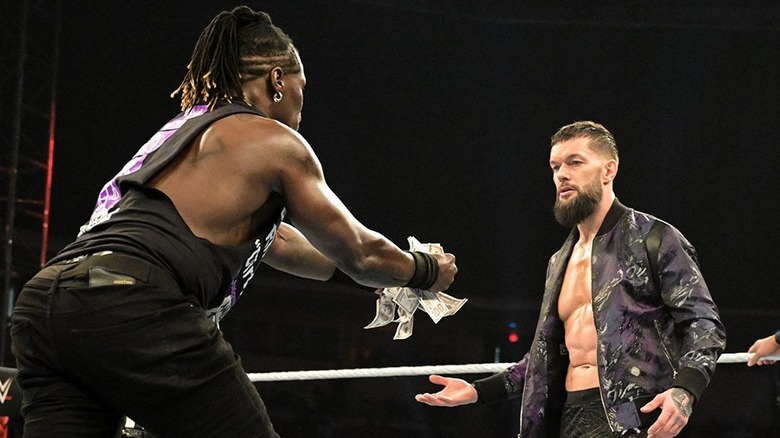 R-Truth handing money to Finn Balor