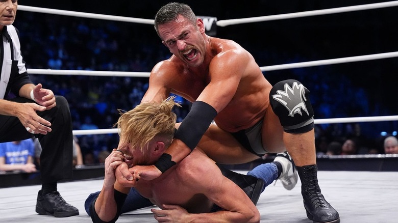 Roderick Strong puts Orange Cassidy in a submission hold in the middle of the ring during a match on AEW TV.