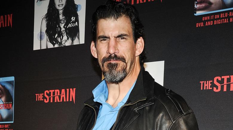 Robert Maillet standing in front of promotional material for The Strain