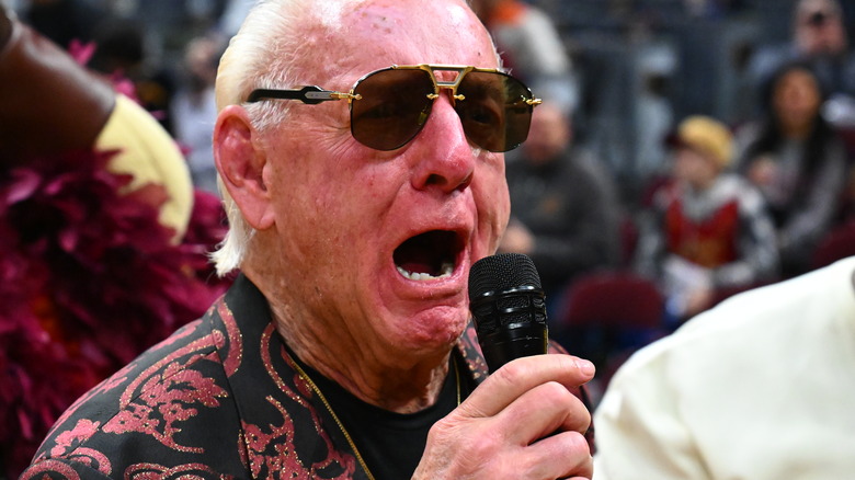 Ric Flair in sunglasses yelling into microphone