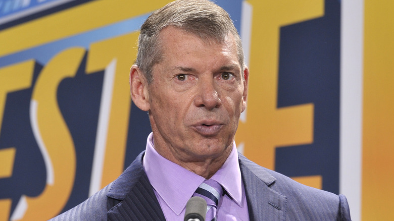 Vince McMahon stands in front of a microphone