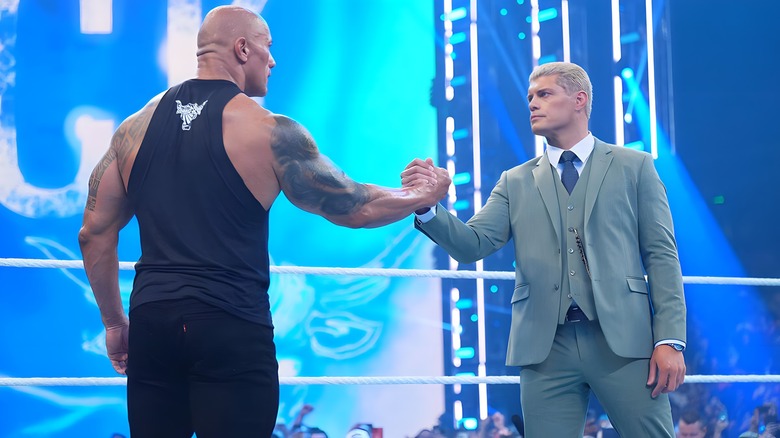 Dwayne "The Rock" Johnson clasps hands with Cody Rhodes