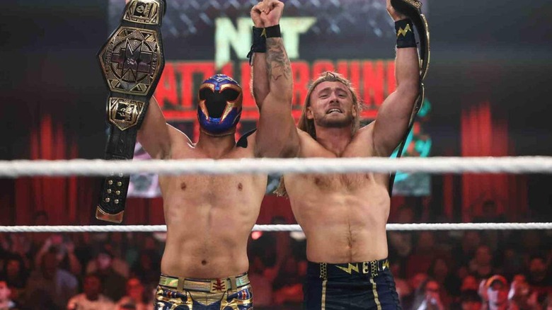 Axiom and Nathan Frazer raise their hands in victory, holding the NXT Tag Team Championships.