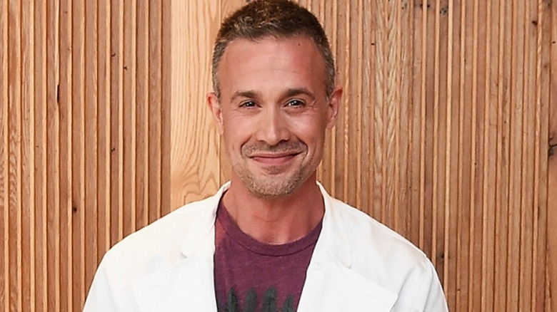 Freddie Prinze Jr. stands in front of a wall