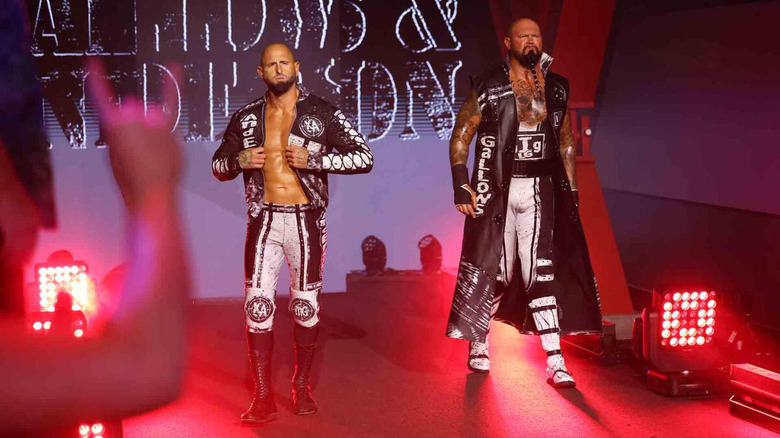 Luke Gallows and Karl Anderson make their way to the ring, cloaked in black gear with white accents.