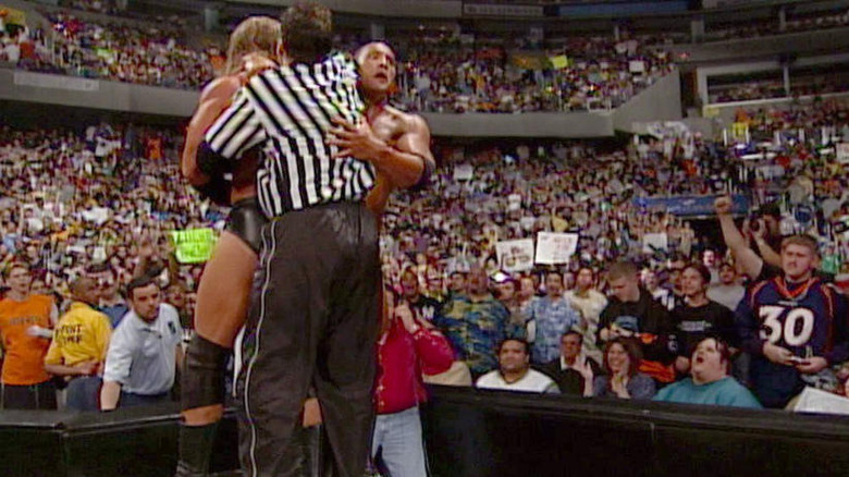 The Rock holding Shane McMahon and Triple H