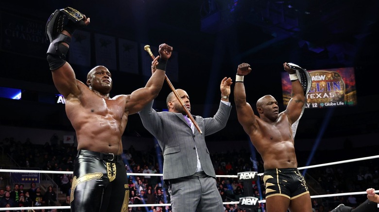 MVP holds up Shelton Benjamin and Bobby Lashley's hands as Benjamin and Lashley hold up the AEW World Tag Team Championships.