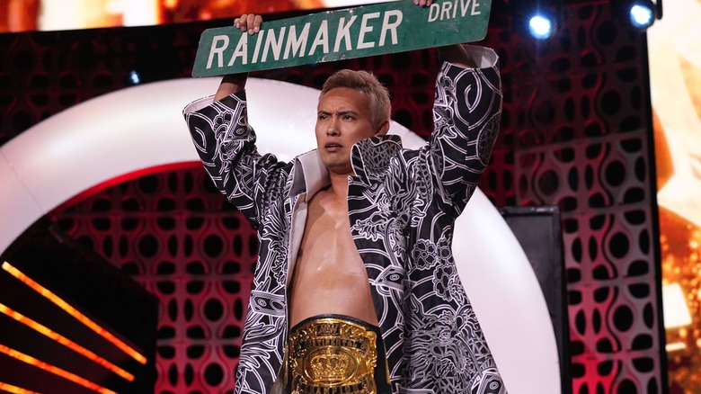 Kazuchika Okada holds up a street sign that says "Rainmaker Drive."