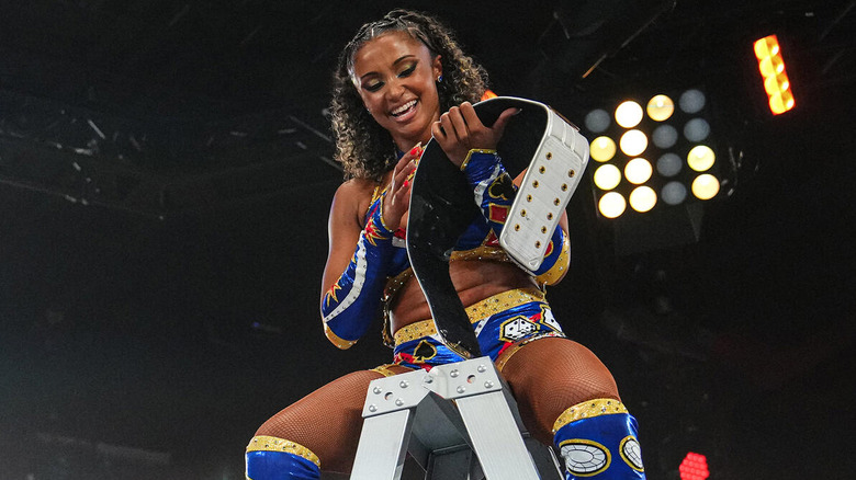 Kelani Jordan holding Nother American title belt atop ladder