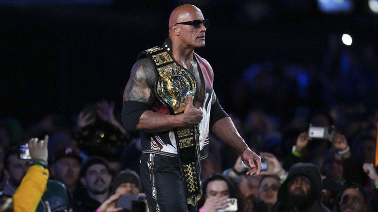 The Rock wearing sunglasses and walking to the ring