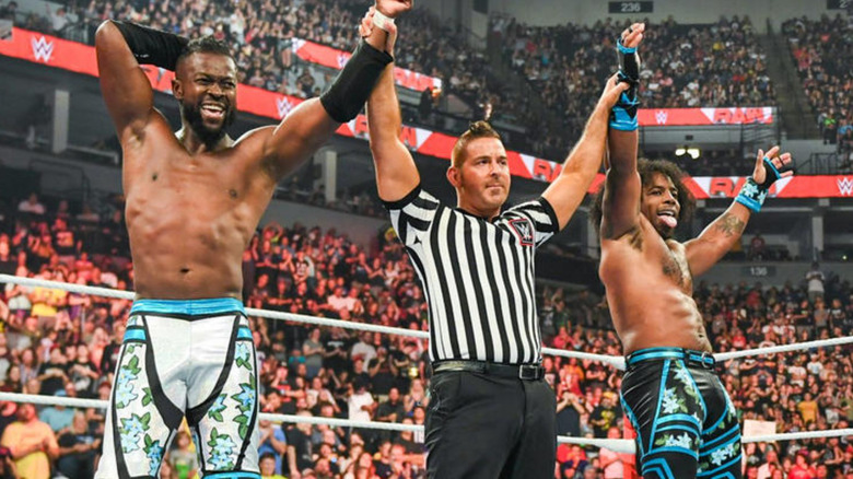 WWE referee holding up hands of Kofi Kingston & Xavier Woods