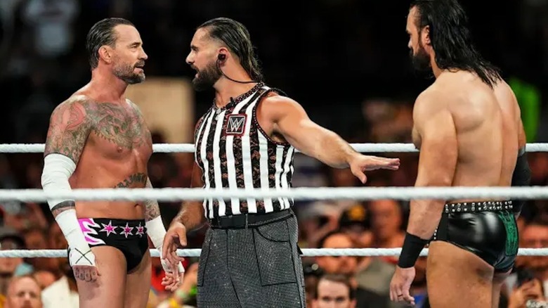 Seth Rollins stands in between Drew McIntyre and CM Punk.