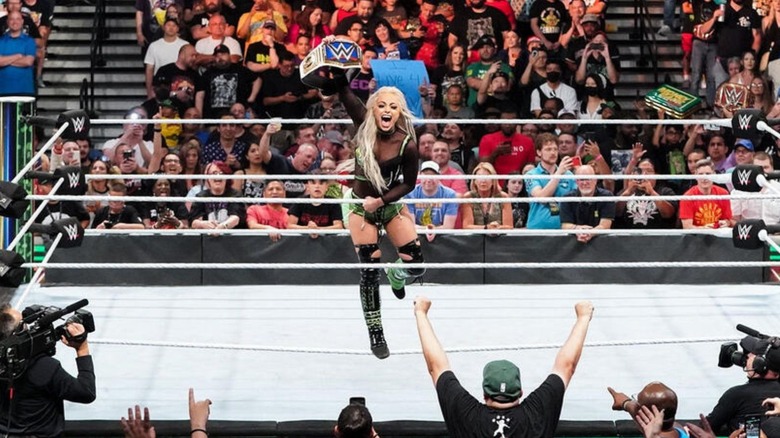 Liv Morgan holds up her newly won SmackDown Women's Championship for the fans on the ropes after defeating Ronda Rousey.