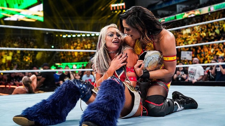 Liv Morgan and Raquel Rodriguez sit in the ring after winning the tag team championships from Ronda Rousey and Shayna Baszler.