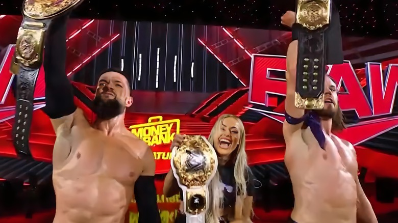 Finn Balor and JD McDonagh hold up their tag titles with Liv Morgan between them