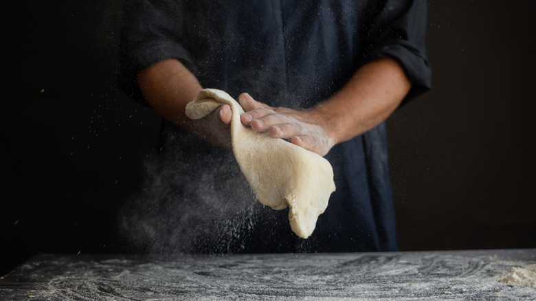 hands kneading pizza dough