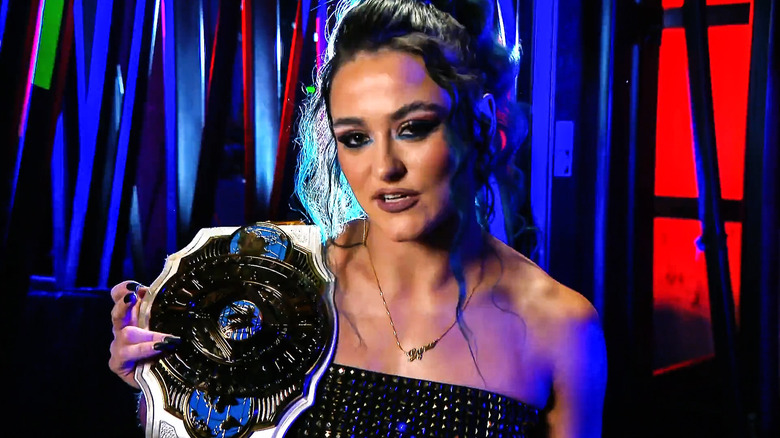 Lyra Valkyria speaks to the camera while holding the Women's Intercontinental Championship on her shoulder.