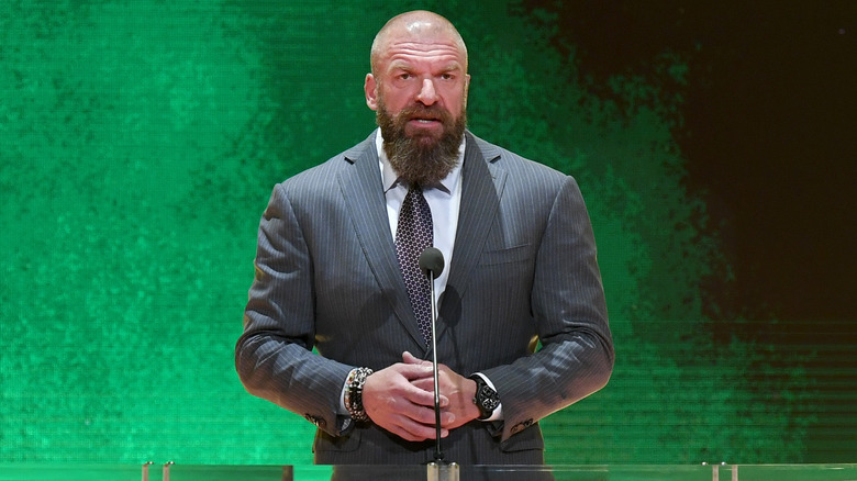 Triple H speaks in front of a green background