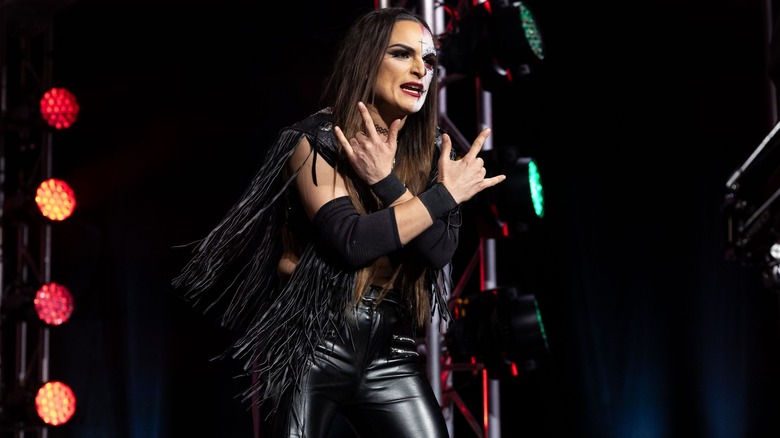 Thunder Rosa throws up two rock-on hand signs across her chest as she makes her entrance.