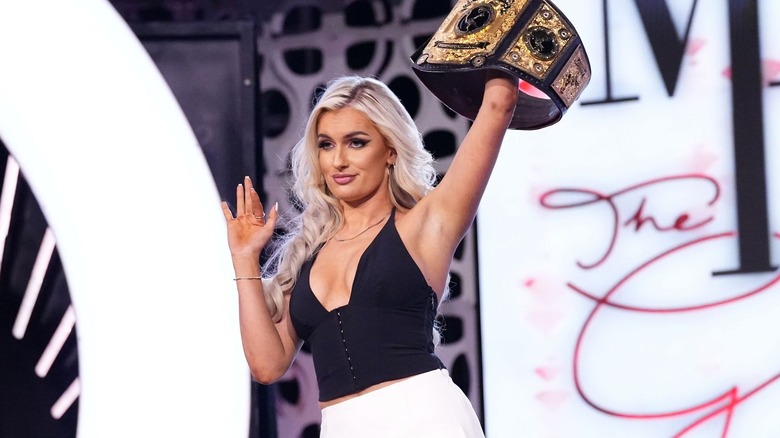 Mariah May waves smugly as she holds up her AEW Women's World Championship.