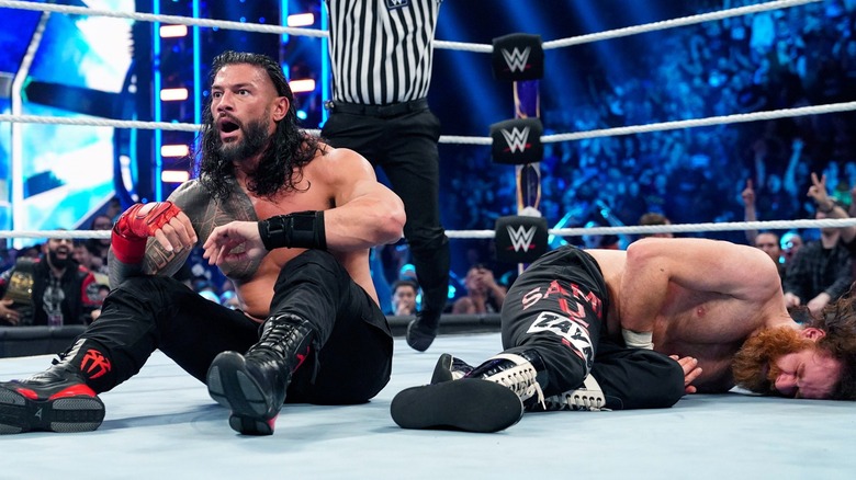 Roman Reigns sits beside a fallen Sami Zayn