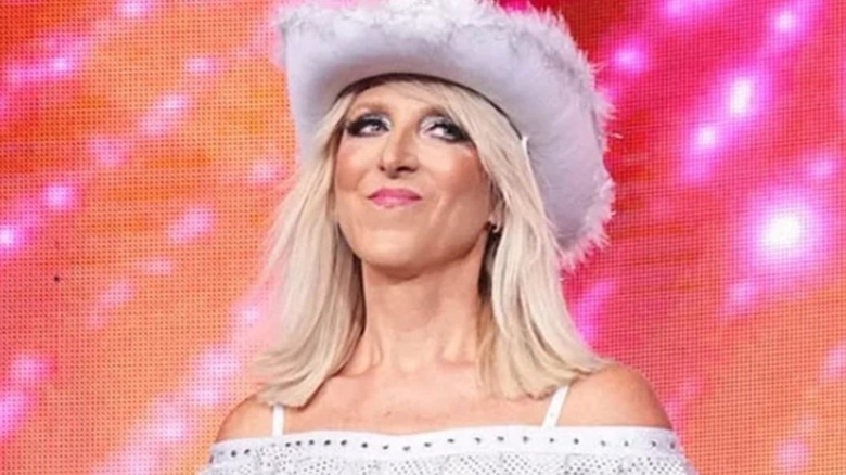 Martha Hart, clad in a cowboy hat, stands on the stage during an announcement on AEW programming.