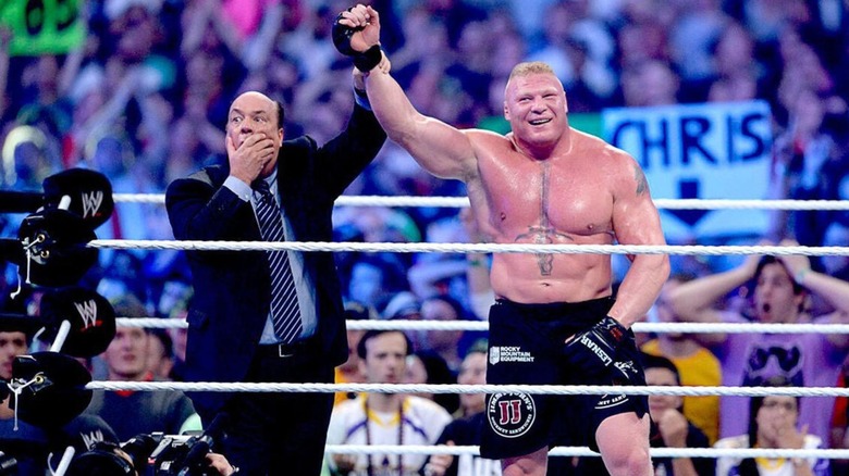 A shocked Paul Heyman raises the hand of a smirking Brock Lesnar after Lesnar defeated The Undertaker and his 21-0 WrestleMania win streak.