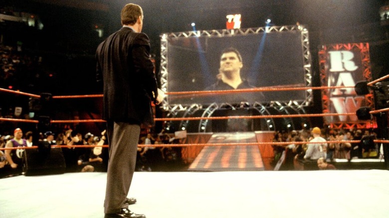 Vince McMahon stands in the ring during an episode of "Raw," looking to the tron where his son, Shane, stands in a ring in WCW.