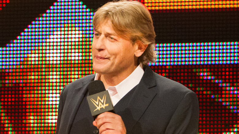 William Regal is holding a microphone