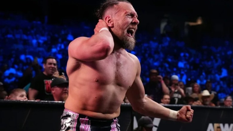 Bryan Danielson stands by the ring, holding his neck, during a match on AEW programming.