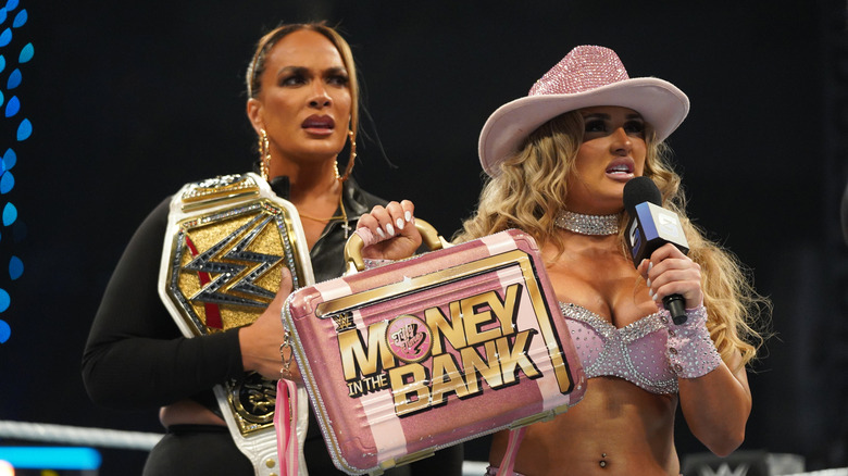 Tiffany Stratton holds herv briefcase in front of Nia Jax