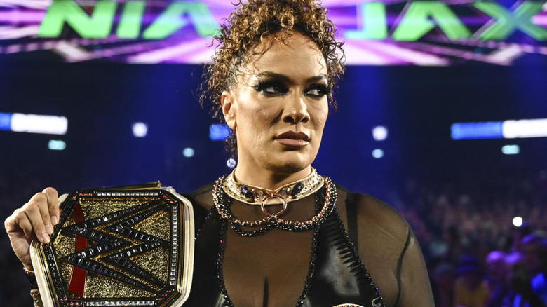 Nia Jax glares off to the side as she holds the WWE Women's Championship on her shoulder.