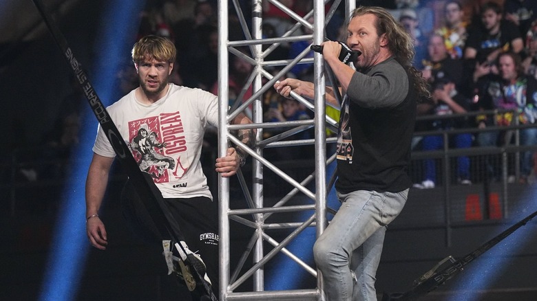 Will Ospreay and Kenny Omega towering a metal pole