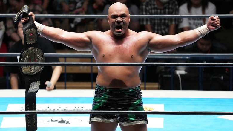 Henare in the ring posing holding a championship