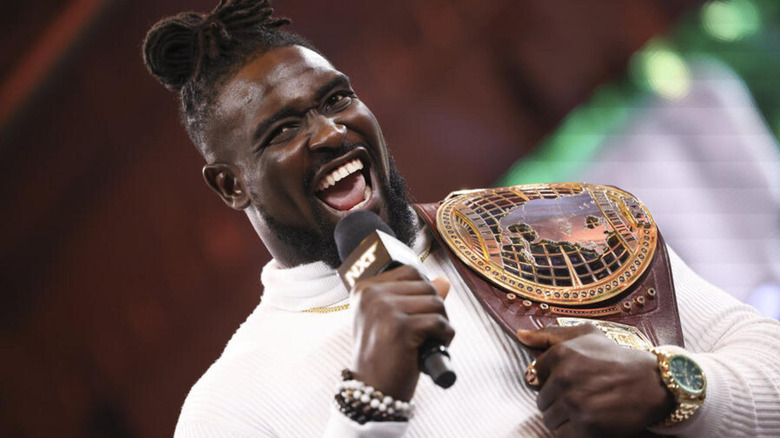 Oba Femi grins with the NXT North American Championship on his shoulders.