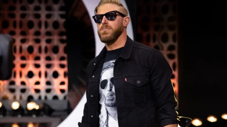 Orange Cassidy, dressed in all black, including his sunglasses, walks down to the ring during an episode of AEW programming.