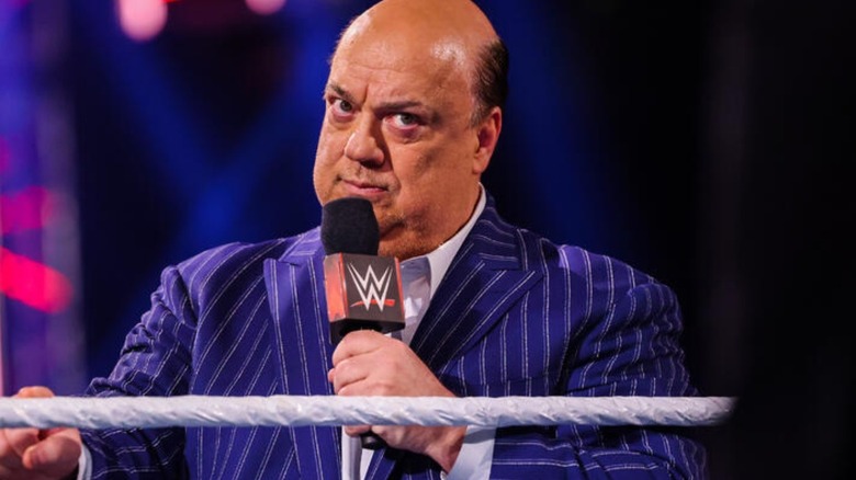 Paul Heyman stands in the ring, holding a microphone