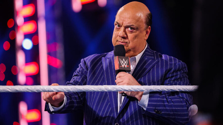 Paul Heyman holds a microphone and glares at an off-screen figure.